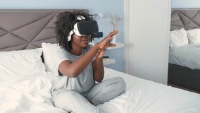 Young african woman experiencing virtual reality on her bed in the morning.