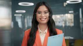 Beautiful happy millennial entrepreneur in blue lens glasses, businesswoman portrait. Pretty business manager. Smiling asian young woman in modern eyewear looking to camera in business office