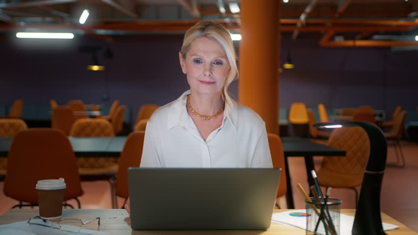 Happy cheerful mature entrepreneur talking to webcamera, doing online video chat job interview sitting at desk. Confident positive businesswoman waving hand at webcam conference video calling office Royalty-Free Stock Footage #1101209169