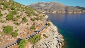 Aerial drone footage of the car driving on a beautiful coastal road on Kefalonia island, Ionian sea, Greece. Beautiful mediterranean landscape in Cephalonia. Rental car during Greek holidays concept