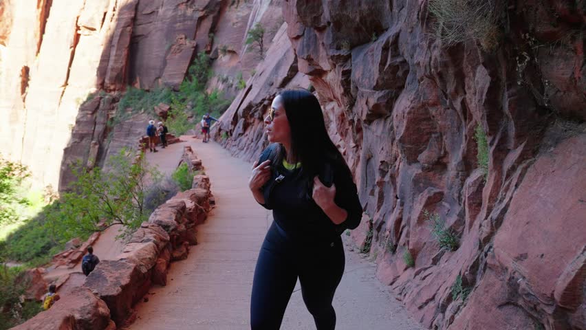 Caucasian woman hiking on trail path in Zion national park with rock formations. Picturesque driftwood and red sand
