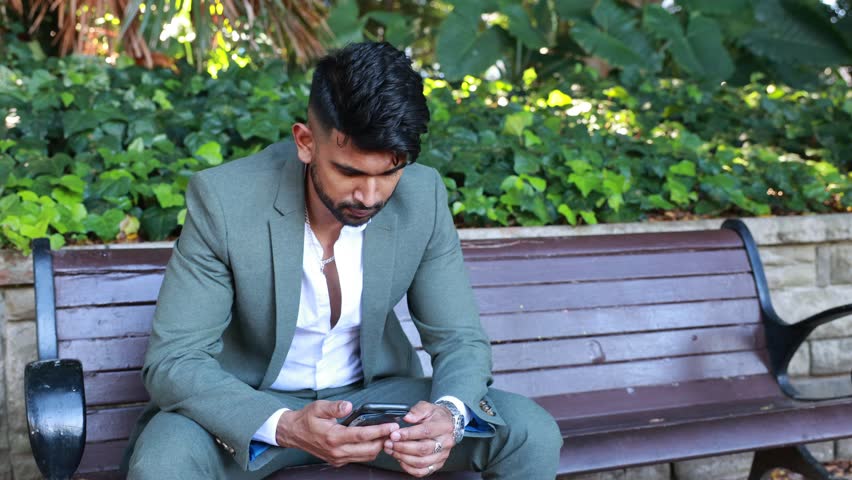 man sitting on a bench and making a phone call