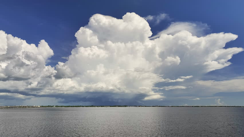 White fluffy cumulonimbus clouds forming from evaporating humidity of ocean water before thunderstorm on summer blue sky. Changing stormy cloudscape weather Royalty-Free Stock Footage #1101211975