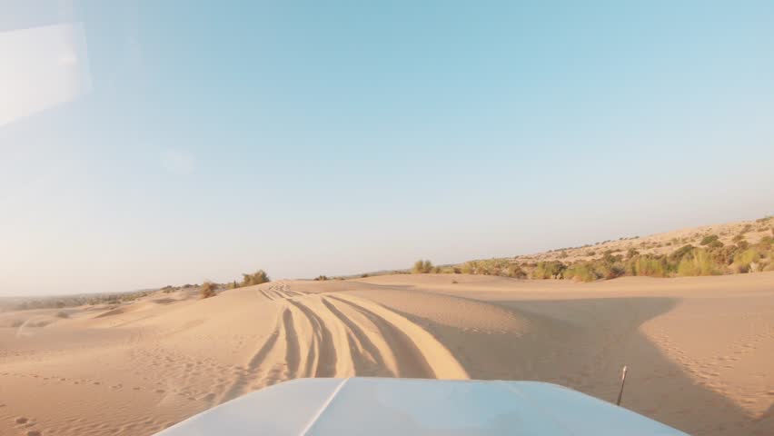 4K POV of a vehicle dune bashing on the sand dunes of the Thar desert at Jaisalmer in Rajasthan, India. Car moves on the desert during the day. Extreme adventure in the desert background. Royalty-Free Stock Footage #1101215685