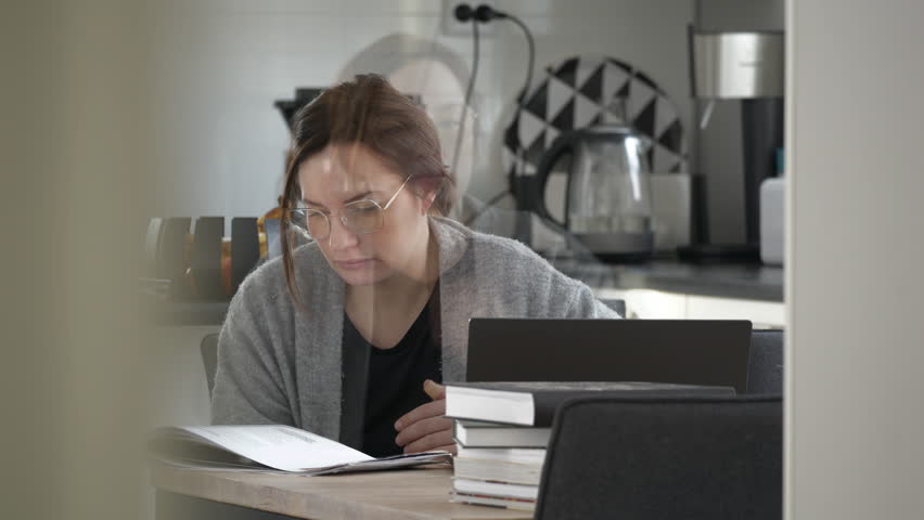 Caucasian woman studying in the kitchen with tenacity. Time lapse