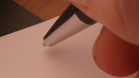 macro clip of a person beginning a printed letter with Dear Mom on a notepad