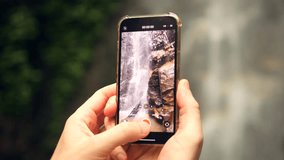 Tourist Hiker Man Shooting Video of Beautiful Jungle Waterfall Using Smartphone 4K Slow Motion Amazing Wild Nature Travel Concept Footage, Thailand.