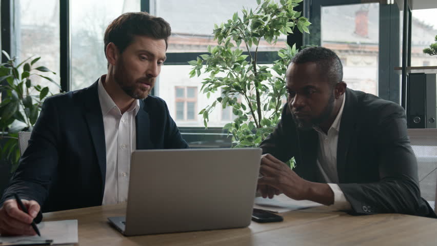 African American businessman listen Caucasian man trader agent check data in documents papers in bank office. Two diverse multiracial businessmen with laptop online project startup business discussion Royalty-Free Stock Footage #1101222625