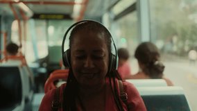 African senior woman listening to music with wireless headphones sitting in the bus - Powered by Shutterstock - Get 15% off with code: PIKWIZARD15
