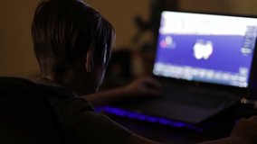 Teenage boy playing a video game on his laptop in the darkness at night. computer games concept