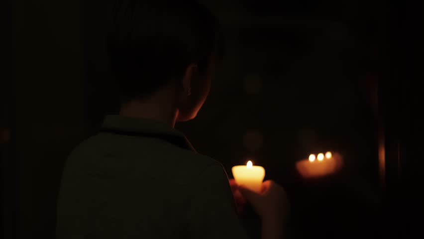teen boy sitting in the dark with candle and reflection in the window. Fear, darkness, abandoned castle concept.