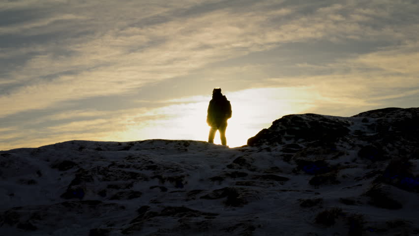 Silhouette shot of a hiker enjoying the sunrise at the peak of Lovstakken, Norway