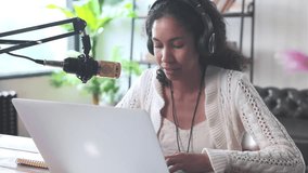 Young happy African American woman radio host takes off headphones and smiles at camera after recording audio podcast for streaming website sits in home studio at table with laptop and microphone - Powered by Shutterstock - Get 15% off with code: PIKWIZARD15