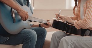 two talented skilled Composers Playing Guitar And Composing Music On Note Book At Home close up cropped video slow motion