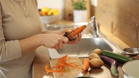 Female peel carrot using vegetable peeler. Close-up of woman's hand at kitchen. Preparing food at home - Powered by Shutterstock - Get 15% off with code: PIKWIZARD15