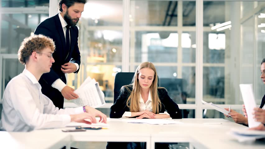Frustrated millennial female worker sitting in middle of table with colleagues and cries because of the excessive workload, stress and aggression of the people around her Royalty-Free Stock Footage #1101225411