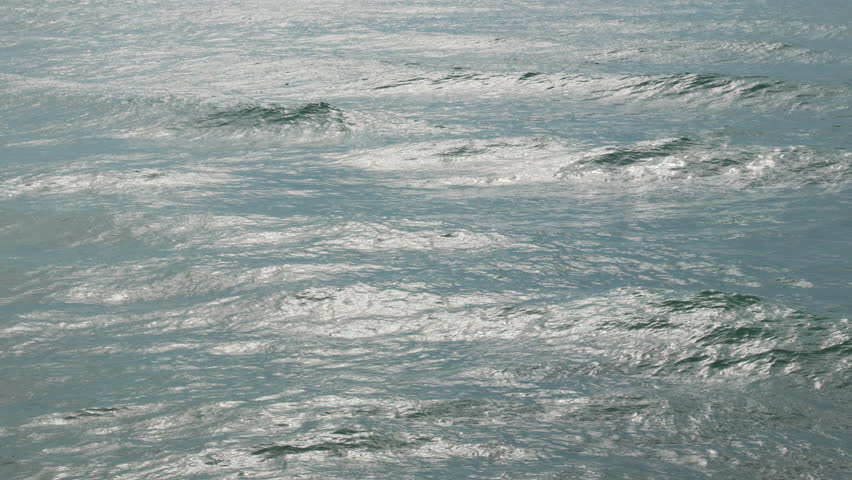 silver sun light reflected as waves break during dramatic morning