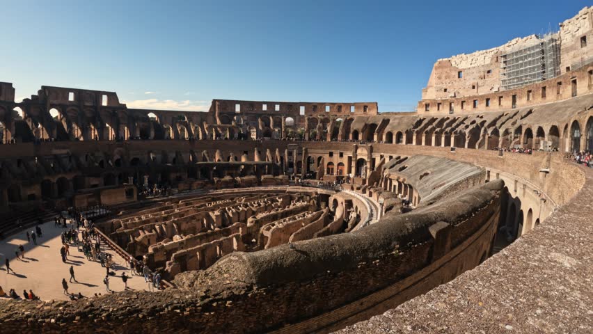 4k wide angle view inside the colosseum with tourists down the bottom exploring the lower section. rome italy