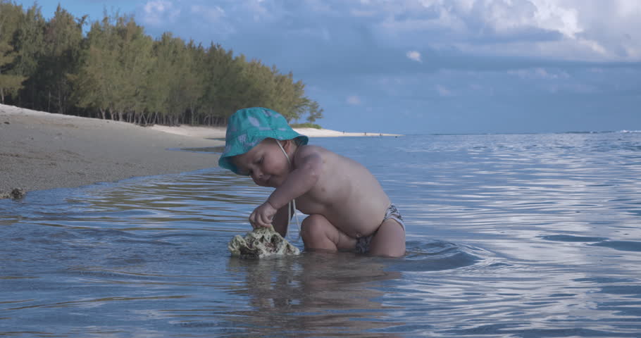 Kid In A Panama Hat Plays In The Water On The Ocean
