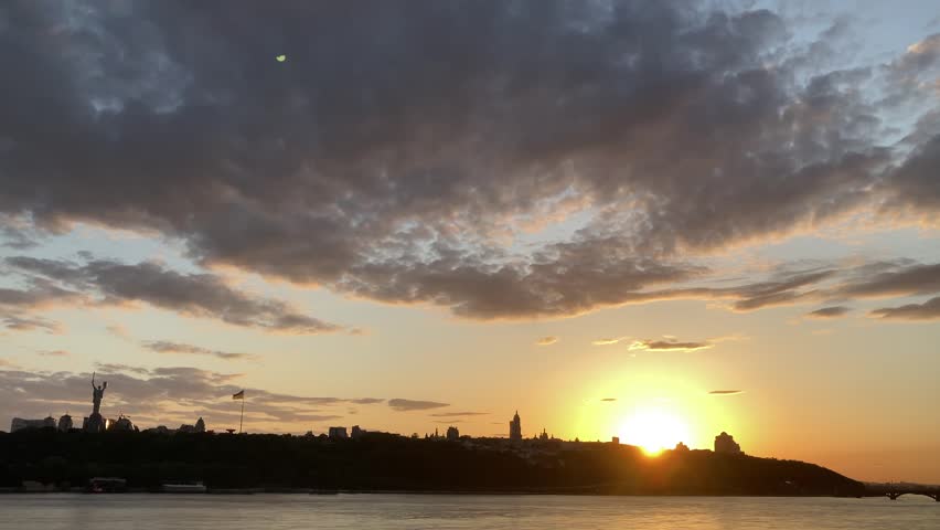 Dramatic colorful sunset over Dnipro river in Kiev, Ukraine. Historical sights of Ukraine. Beautiful scenic view of Kyiv. Sunset over the Dnieper River in Kiev. View of the river with waves