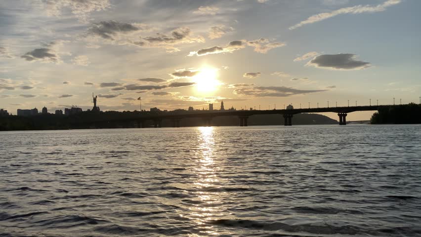 Historical sights of Ukraine. Beautiful scenic view of Kyiv. Sunset over the Dnieper River in Kiev. View of the river with waves. Dramatic colorful sunset over Dnipro river in Kiev, Ukraine, travel