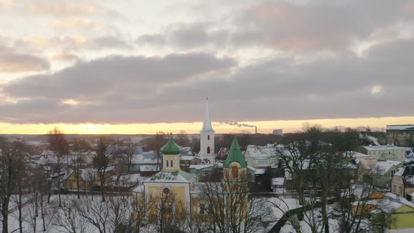 Orthodox and a Lutheran Church in winter dusk light. Aerial cinematic view. Christianity religion concept. Filmed in Haapsalu, Estonia