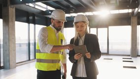 Workers Partners Holding Drawing Tablet Walking at Modern Unfinished Business Center. Male Civil Engineer and Young Female Building Architect Discussing Project Work on a City Construction Site. - Powered by Shutterstock - Get 15% off with code: PIKWIZARD15