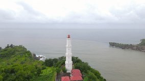 Drone shot of white lighthouse on the coral cliff - Baron Beach, Indonesia