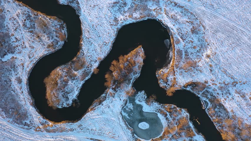 winter aerial top view to river bending in fields at sunset, rotated shot. Ukraine