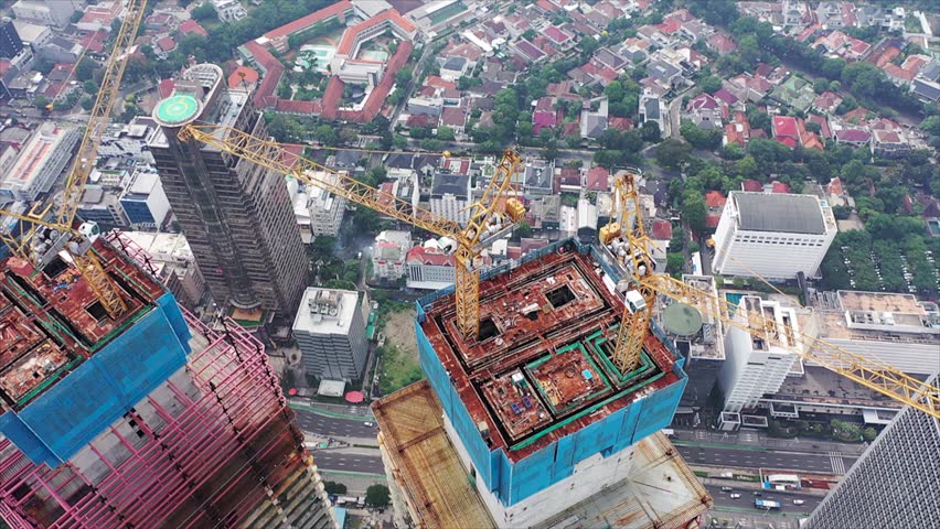 Aerial view of a skyscrapers under construction with huge cranes in Jakarta. Blue sky on a background Royalty-Free Stock Footage #1101249931