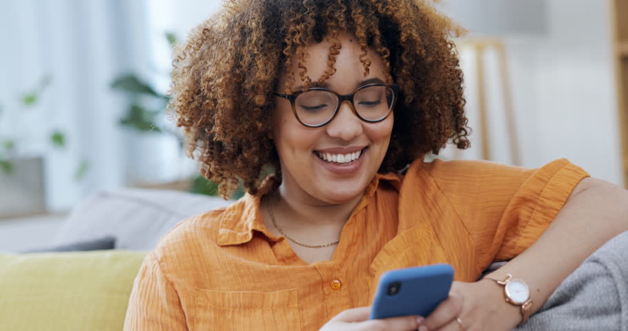 Happy woman laughing on a phone and sofa for funny internet meme, social media post or texting on mobile app. Young black person on couch or living room typing on a cellphone, smartphone or web chat