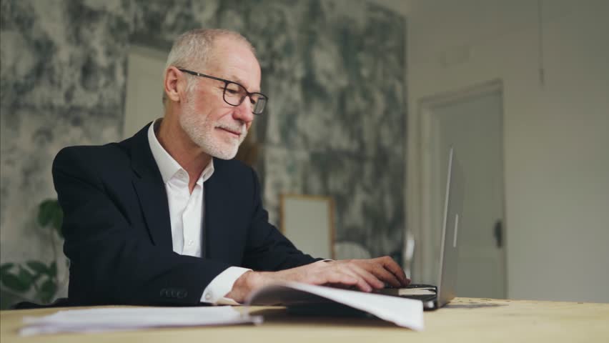 Businessman is working on a laptop. man typing and examining budget documents. | Shutterstock HD Video #1101258601