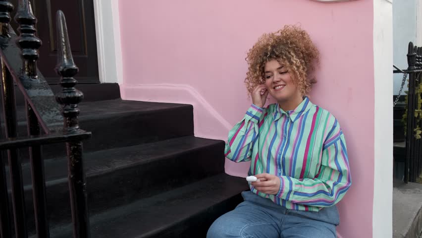 Young woman sits on stairs listening to music