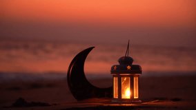 Eid Mubarak Greetings video, Ramadan Lantern lamp and Crescent moon shape on the beach with Sunset sky