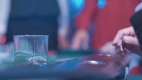 Man with suit in casino drinks whiskey and throws poker chips as bet, detail shot - Powered by Shutterstock - Get 15% off with code: PIKWIZARD15