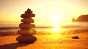 Balanced rock pyramid on pebbles beach, sunny day and clear sky at sunset. Golden sea bokeh on background. Selective focus, zen stones on sea beach, meditation, spa, harmony, calm, balance concept. - Powered by Shutterstock - Get 15% off with code: PIKWIZARD15
