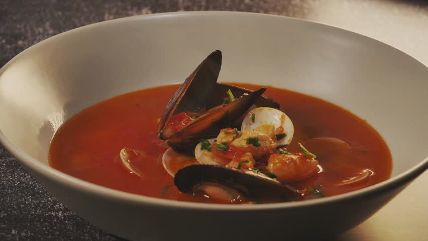 Tasty fish soup boiling. Spreading parsley on  Mediterranean fish soup with mussels, clams, prawns, tomato. Tasty hot soup Royalty-Free Stock Footage #1101264105