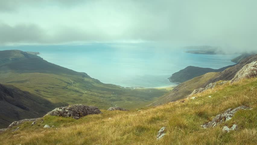 A hiker at the top of the mountain views the magnificent landscape of the sea bay. Isle of Skye. Bla Bheinn, Isle of Skye, Scotland 