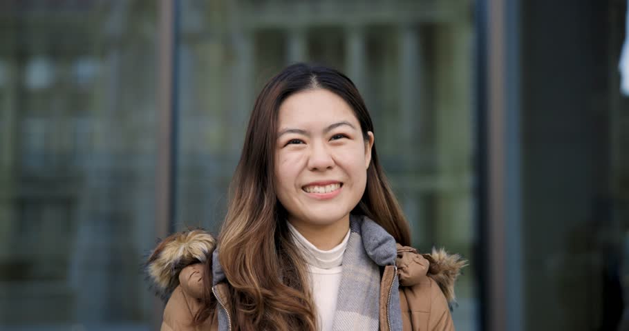 Young happy Chinese woman slow motion portrait laughing and looking at camera - College student showing happiness and confidence, lifestyle and diversity concepts