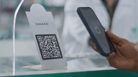 A close-up shot of a hand of a customer scanning a barcode to pay e-money to an electronic bank account or online UPI transfer in a general or grocery store with a shopkeeper in the background. - Powered by Shutterstock - Get 15% off with code: PIKWIZARD15