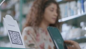 A close-up shot of a hand of a customer scanning a barcode to pay e-money to an electronic bank account or online UPI transfer in a general or grocery store with a smiling woman in the background - Powered by Shutterstock - Get 15% off with code: PIKWIZARD15