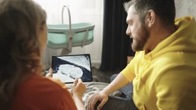 A pregnant couple looks at a picture of a baby on an ultrasound scan. Happy parents-to-be laugh and rejoice. High quality 4k footage - Powered by Shutterstock - Get 15% off with code: PIKWIZARD15