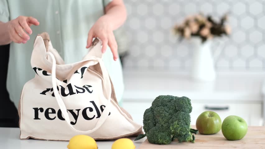A young woman chooses a zero waste lifestyle. Woman takes out vegetable and fruits from bag after shopping. Waste Reduction and Reducing. Reusable cloth produce bag. Plastic alternatives for food Royalty-Free Stock Footage #1101266391