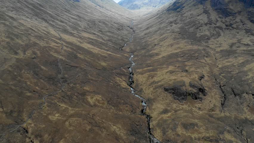 Aerial view of highlands in Scotland, with clouds over the famous mountains known as Three Sisters of Glencoe - Moody weather in Scottish highlands - Background ready image of beautiful landscape