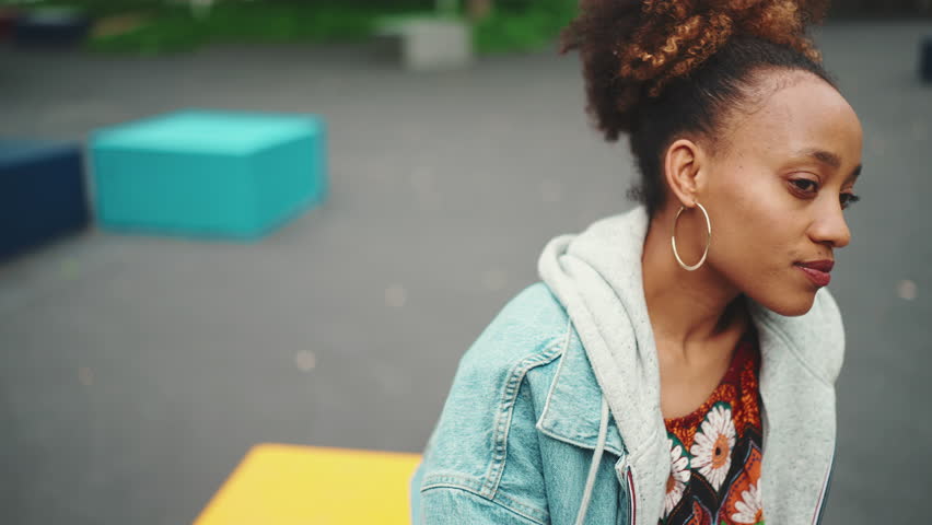 Clouse-up of girl with ponytail wearing denim jacket, in crop top with national pattern looking around. Slow motion