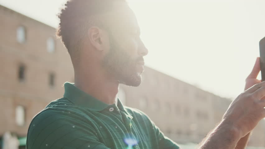 Close-up profile of young man taking photo on mobile phone