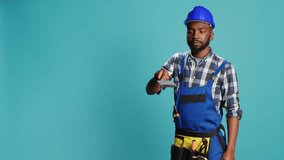 African american man painting walls with brush in studio, using renovating tools to change color. Professional builder working with paintbrush on carpentry equipment over blue backdrop. - Powered by Shutterstock - Get 15% off with code: PIKWIZARD15
