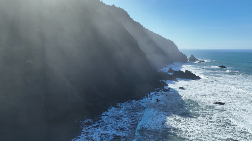 Bright sunlight shines on the rugged southern coast of Oregon, part of the Samuel H. Boardman State Scenic Corridor. This wild, rocky coastline is thickly forested and full of amazing viewpoints.