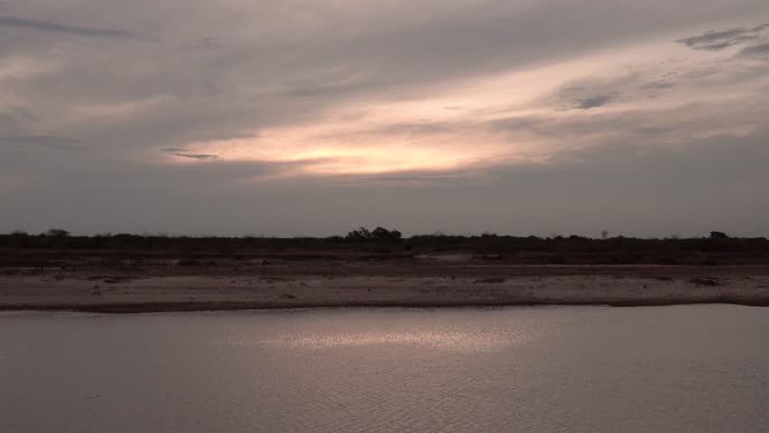 Panorama view of the river under a dramatic sunset sky. Beautiful sunlight and clouds reflection in the water surface. 