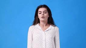 4k video of one girl showing thumb down on blue background.